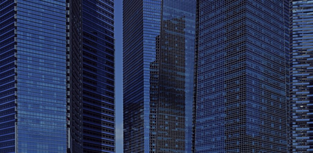 Modern glass skyscrapers reflecting blue sky and clouds.